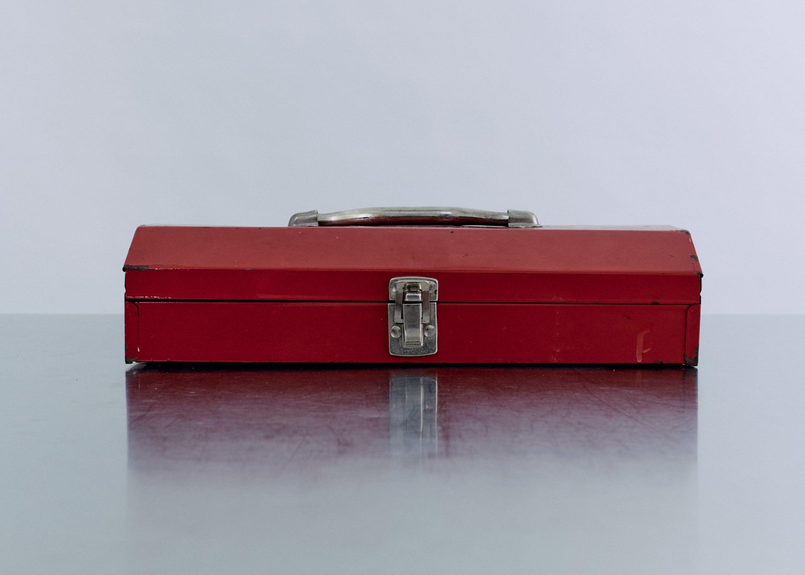 Red toolbox on a reflective surface with a light gray background